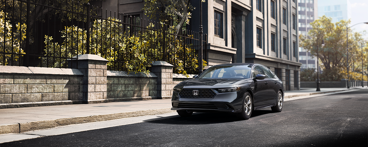 3/4 front view of a grey Accord parked curbside in an upscale urban neighbourhood in the day.