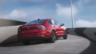 3/4 rear view of red Accord driving up the ramp of an outdoor parkade.
