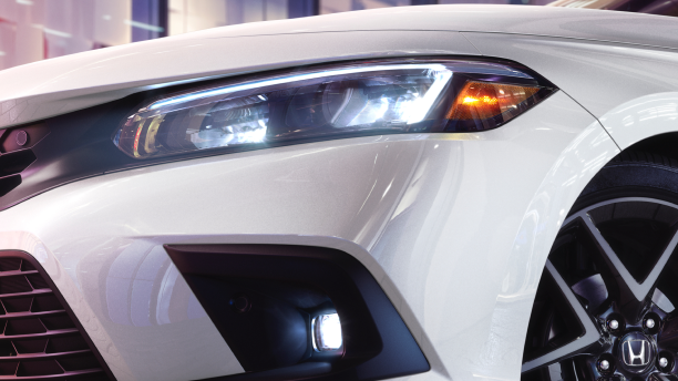 Closeup of headlight on a white Hatchback. 