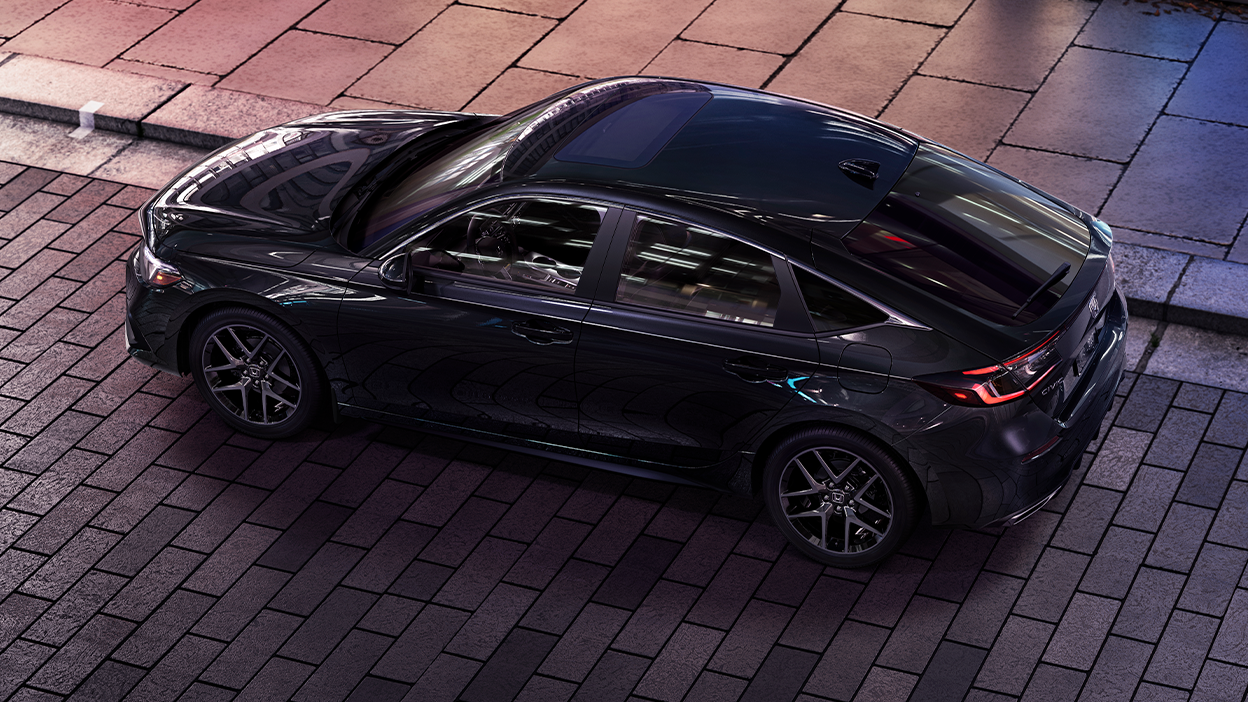 3/4 bird’s eye view of black Hatchback parked on brick city road.