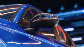 Gros plan du rétroviseur extérieur d’une Civic berline bleue dans un espace sombre comme un entrepôt.