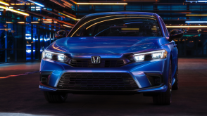 Front view of a parked blue Civic Sedan in a dark warehouse-like space.