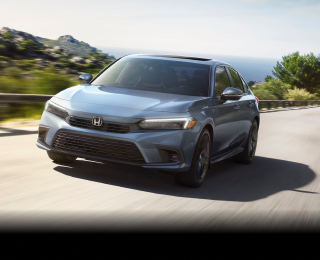 Front view of a grey Civic Sedan driving toward camera on an oceanside highway.