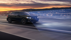 3/4 front sideview of black Civic Si driving on a highway at dusk. Blue sensor lines emit from the front. 