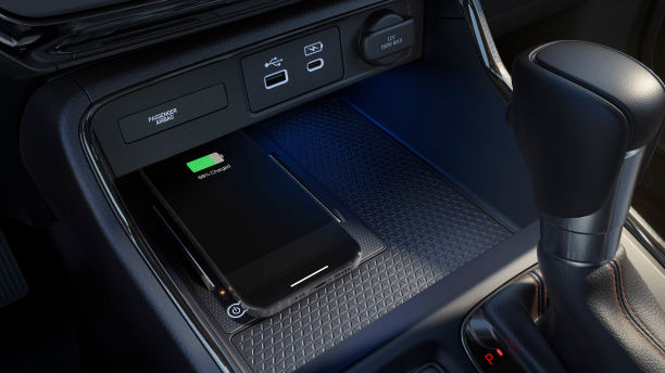 Closeup of smartphone charging on wireless charging pad in centre console.
