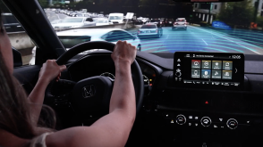 Interior view of woman driving CR-V in city highway traffic. Blue sensor waves and lines emit from the front. 