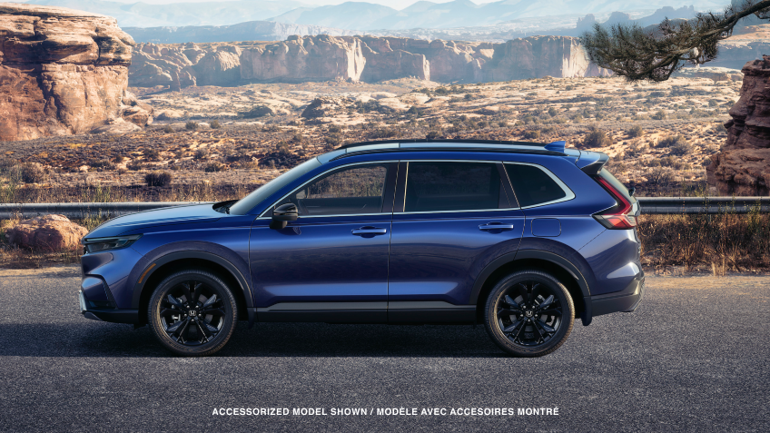 3/4 front view of grey CR-V, with two bikes on the roof racks, driving on a winding desert canyon highway.