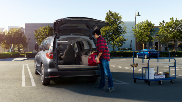 Man loading up Odyssey trunk in empty parking lot.
