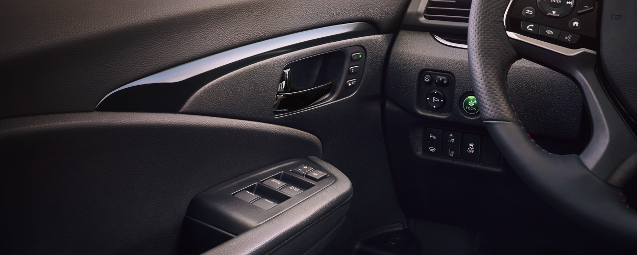 Closeup of power window buttons and ECON mode button on dash.