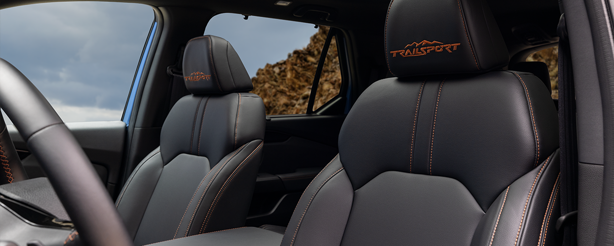 Plan des sièges avant du Pilot TrailSport, avec coutures orange et logo « TrailSport » sur les appuie-tête et nouveau toit ouvrant panoramique électrique à un bouton. 