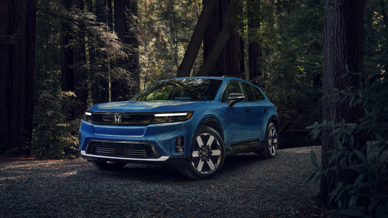 Plan de trois quarts avant d’un Prologue bleu stationné dans une forêt tempérée.