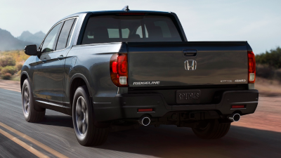 3/4 rear view of Ridgeline driving on desert highway, showcasing dual exhaust.