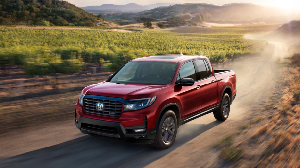 3/4 front view of red Ridgeline driving on dirt round in wine country.