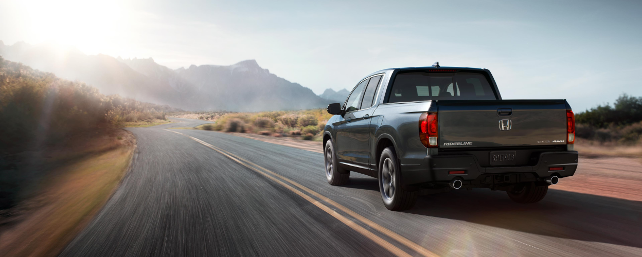 3/4 rear view of Ridgeline driving on desert highway.
