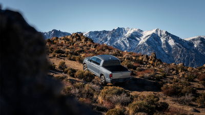 3/4 wide view of grey Ridgeline driving uphill in tundra