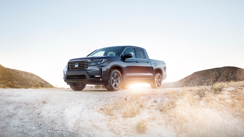 3/4 front view of parked grey Ridgeline in desert hillside.	