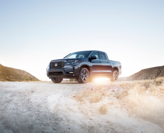3/4 front view of parked grey Ridgeline in desert hillside.	